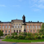 L'image représente un grand bâtiment de l'Université d'Uppsala, mettant en avant un design architectural classique. L'édifice présente une façade symétrique avec des fenêtres en arc au rez-de-chaussée et des fenêtres rectangulaires aux étages supérieurs, toutes encadrées de moulures décoratives.