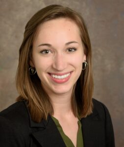 The image features Danielle Meadows with shoulder-length brown hair, wearing a dark blazer and a green top.